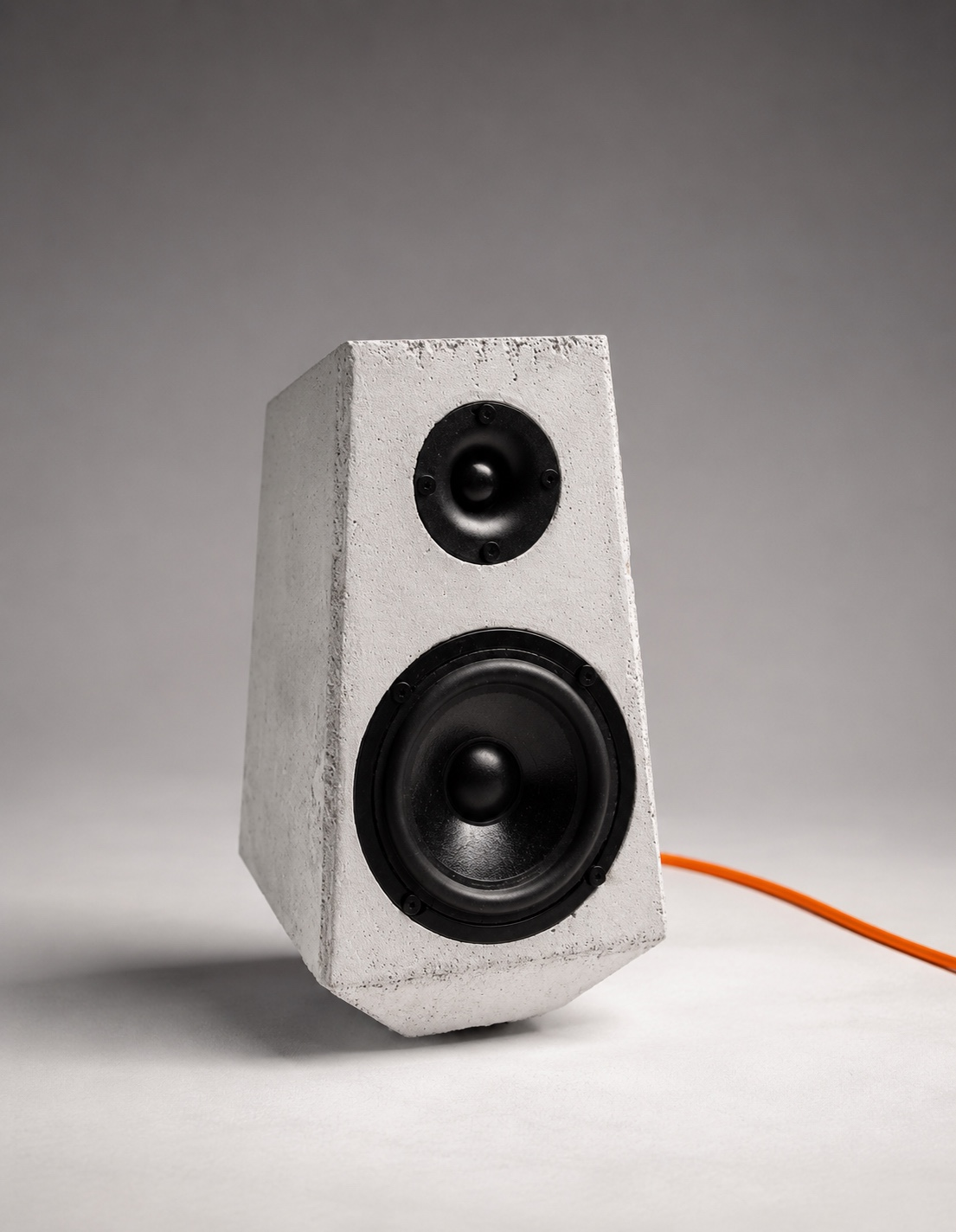 Concrete Speaker 01: a white cast concrete loudspeaker with black drivers and an orange cable